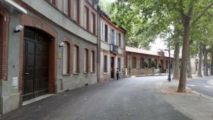 an empty street next to a building with a tree at Résidence le Pastel François Verdier in Toulouse