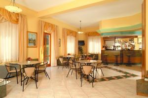sala de estar con mesas y sillas y cocina en Hotel La Conchiglia, en Marciana Marina