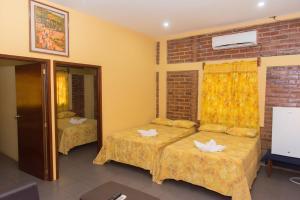 a room with two beds and a brick wall at Tropiclub Playa El Cuco in El Cuco