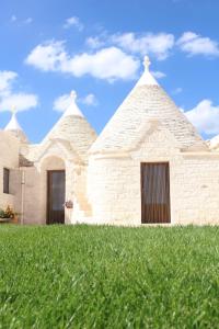 a building with two spires on top of a grass field at I Trulli del Mulino in Locorotondo +17 photos