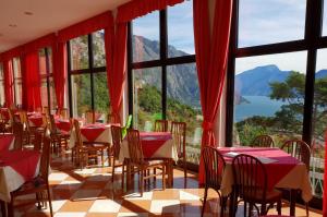 restauracja ze stołami i krzesłami oraz dużym oknem w obiekcie Village Bazzanega - Montagnoli Group w Tremosine Sul Garda