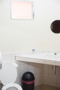 a bathroom with a toilet and a sink and a window at Tropiclub Playa El Cuco in El Cuco