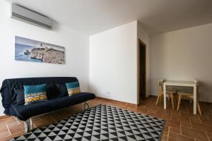 een woonkamer met een zwarte bank en een tafel bij Pé na Areia - Guest House in Vila Real de Santo António