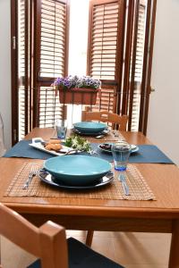 a wooden table with blue plates and glasses on it at Casa Vacanze Il RossAntico in Modica