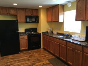 une cuisine avec des armoires en bois et un réfrigérateur noir dans l'établissement Beach Fantasy Apartment Suites, à Old Orchard Beach