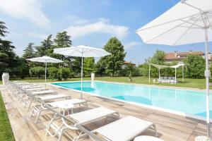 una piscina con sedie a sdraio e ombrelloni bianchi di Residenza Cartiera 243 Country House a Villorba