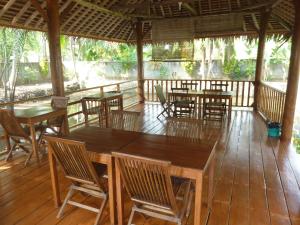 ein Restaurant mit Tischen und Stühlen auf einer Holzterrasse in der Unterkunft Java Lagoon in Pangandaran