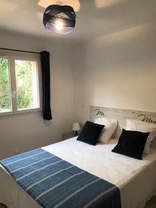 a bedroom with a large white bed with black pillows at Mini-villas Célia à BONIFACIO in Bonifacio