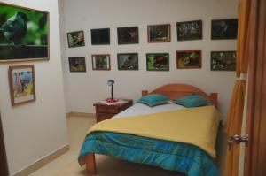 Schlafzimmer mit einem Bett und Bildern an der Wand in der Unterkunft Birdwatchers House y Lodge in Mindo