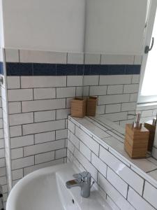 ein Badezimmer mit einem Waschbecken und einer weiß gefliesten Wand in der Unterkunft Ferienwohnung Kröpelin in Kröpelin