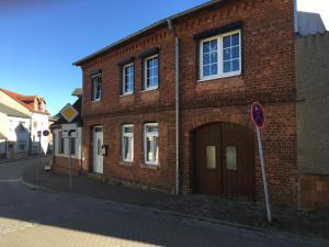 ein Backsteingebäude mit einer großen Tür auf einer Straße in der Unterkunft Ferienwohnung Kröpelin in Kröpelin