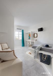 a white living room with a couch and a tv at Manios Suites in Agia Anna Naxos