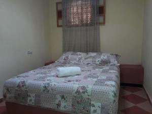 a bedroom with a bed with a blanket and a window at Camping Auberge Zebra in Ouzoud