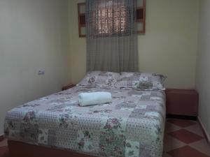 ein Schlafzimmer mit einem Bett mit einer Decke und einem Fenster in der Unterkunft Camping Auberge Zebra in Ouzoud