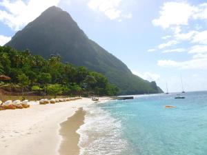 a beach with a mountain in the background and the ocean at Apartment Soleil- Because Location really is everything! in Soufrière