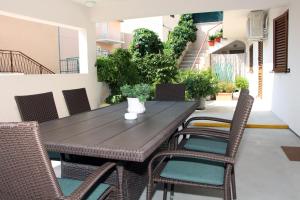 a wooden table and chairs on a patio at Apartmani TEO in Tisno