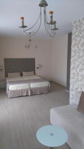 a bedroom with a bed and a couch and a chandelier at Guest House Adriya in Primorsko
