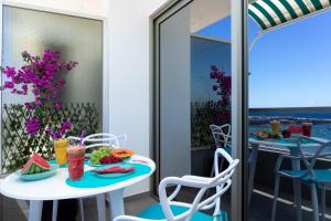 ラスパルマス・デ・グランカナリアにあるFrontline with Blue Viewsのテーブルと椅子、バルコニー(食べ物付)