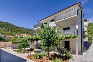 a white building with a tree in front of it at Apartmani Dule Komiza in Komiža