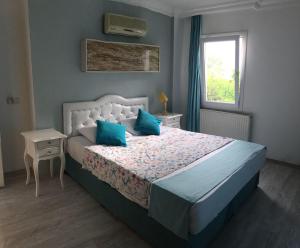 a bedroom with a bed with blue pillows and a window at Camlikosk Apart Hotel in Bodrum City +72 photos