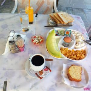 uma mesa com um prato de comida para o pequeno-almoço e uma chávena de café em Sun City em Kato Daratso