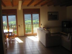 ein Wohnzimmer mit einem Sofa, einem Tisch und Fenstern in der Unterkunft Cal Font (RCP) in Pla de Sant Tirs