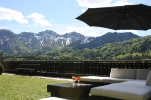 a patio with a couch and an umbrella and mountains at Hotel Lindwurm in Bad Goisern