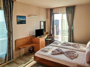 a hotel room with two beds and a desk and a television at Empera H-l in Sunny Beach +61 photos