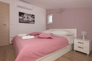 a bedroom with a large bed with pink sheets and pillows at APARTMANI VUJČIĆ in Makarska