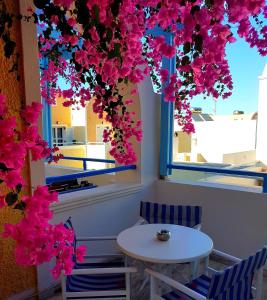 een tafel en stoelen in een kamer met roze bloemen bij Hotel Zeus in Kamari