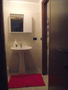 baño con lavabo y alfombra roja en La Fisarmonica, en Valdieri