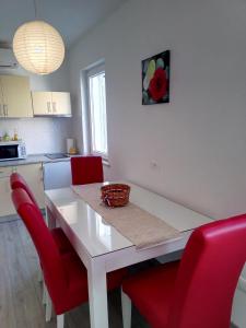 Apartment Luka في ماكارسكا: مطبخ مع طاولة بيضاء وكراسي حمراء
