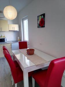 a kitchen with a white table and red chairs at Apartment Luka in Makarska