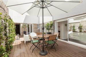 a table and chairs with an umbrella on a deck at Ana`s Houses in Guimarães