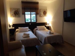 カラバルディナにあるMiramar Habitacionesのベッド2台とテレビが備わるホテルルームです。