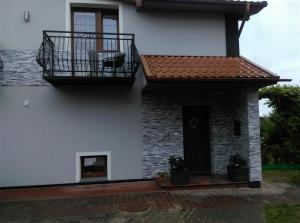 a white house with a balcony and a door at Pokoje u Jolanty in Władysławowo