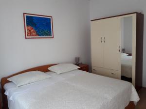 a bedroom with a white bed and a picture on the wall at Apartment Kornic 3 in Kornić
