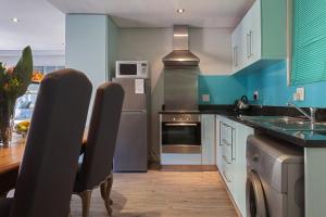 uma cozinha com armários e electrodomésticos azuis e brancos em St Georges 304 by CTHA na Cidade do Cabo
