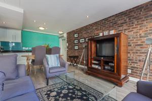 uma sala de estar com uma televisão e uma parede de tijolos em St Georges 304 by CTHA na Cidade do Cabo