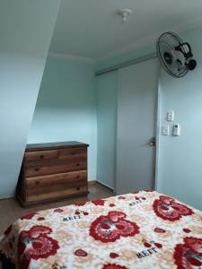 a bedroom with a bed and a dresser and a fan at Casa de amigos e parentes in Eunápolis