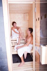 un hombre y una mujer sentados en una sauna en Fabrika Hotel, en Humpolec