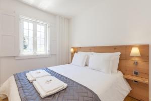 um quarto com uma cama branca com duas toalhas em Ana`s Houses em Guimarães
