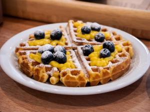 a plate of waffles with fruit on top on a table at Hotel Montecarlo in Rimini