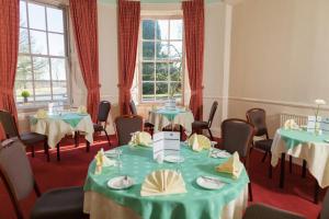 a conference room with tables and chairs and windows at Woodland House Hotel in Dumfries