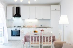 a kitchen with white cabinets and a table and chairs at Guest House Simoni in Prigradica