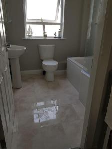 a bathroom with a toilet and a sink and a window at Spire View Townhouse in Ballycastle +27 photos