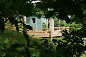 una pequeña casa azul con terraza de madera en The Lookout Shepherd's Hut, en Dolton