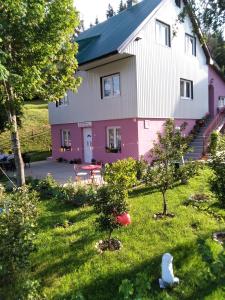 una casa rosa y blanca con árboles en el patio en Apartments Obradović Milan, en Žabljak