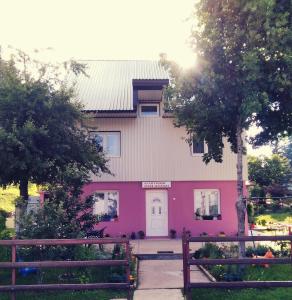 ein rosa Haus mit einem Zaun davor in der Unterkunft Apartments Obradović Milan in Žabljak
