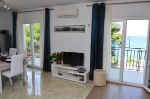 a living room with a television and a balcony with the ocean at Apartment A. Žižić in Slatine